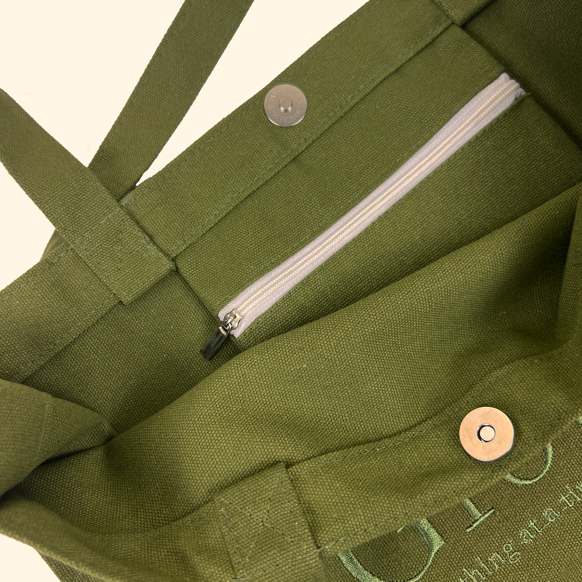 Close up of inside the green tote bag with zipper pocket and magnetic clasp closures